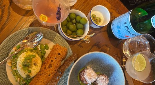 over head shot of the table laid out with couple of small dishes including arancini, olives and drinks