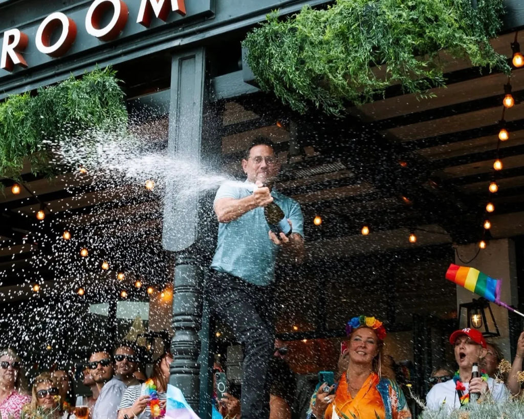 The Salt Room - a man splashing prosecco on the terrace of the venue during Pride Weekend