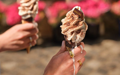 two hand holding melting ice creams