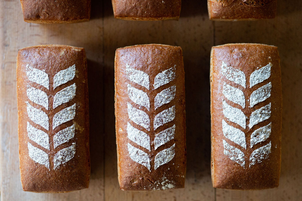 pretty artisan loaves sat side by side on a wooden shelf - at the Open Bakery Brighton