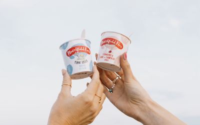 two hands holding ice cream in cup