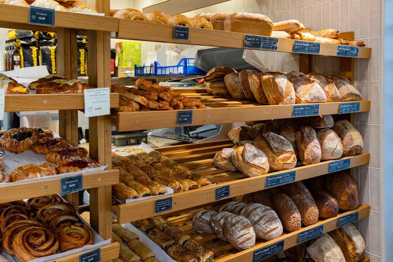 wooden shelves filled with various breads and pastires at Open Bakery Queens Park