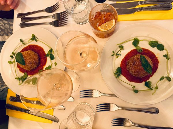 over head shot of the two plates with giant rich arancino, coated with breadcrumbs and filled with ragù, buffalo mozzarella and peas
