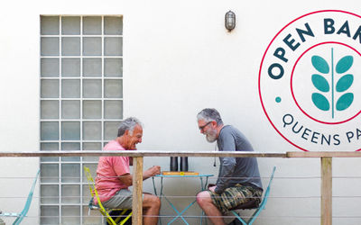 two gents playing a board game outside the Open Bakery in Queens park