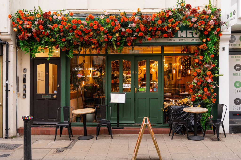 A green painted exterior at Kemptown cafe with orange flower garland.