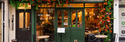A green painted exterior at Kemptown cafe with orange flower garland.