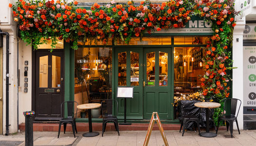 A green painted exterior at Kemptown cafe with orange flower garland.