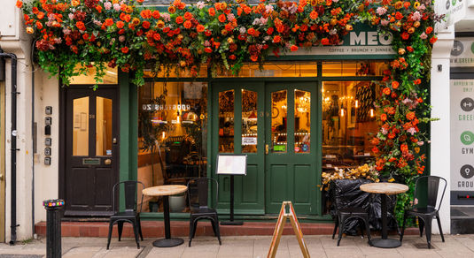 A green painted exterior at Kemptown cafe with orange flower garland.