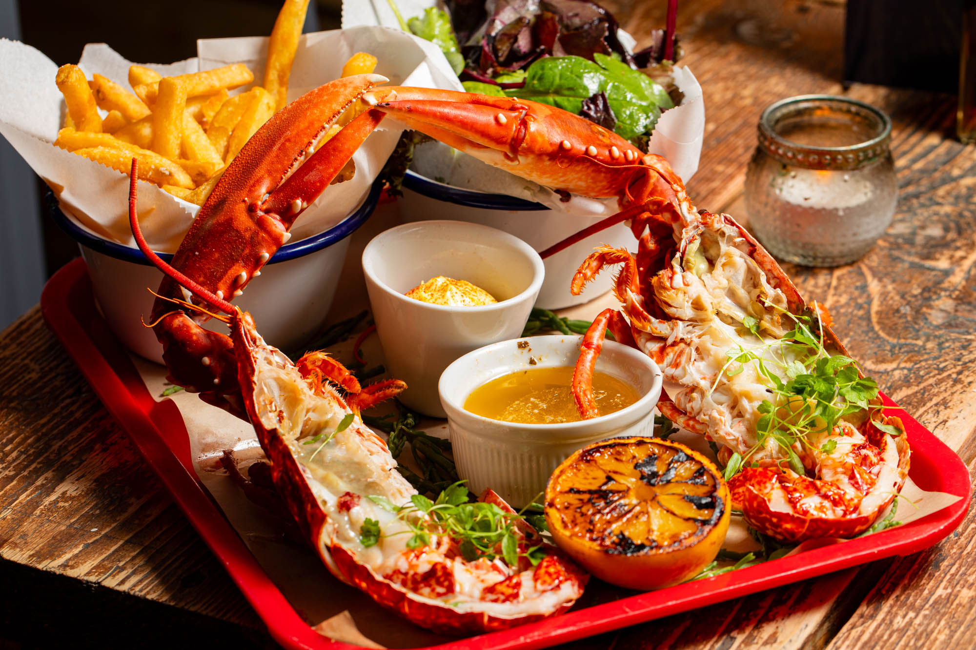 seafood tray with lobster, sauces, piece of orange and chips, served on wooden table at Crabshack Worthing