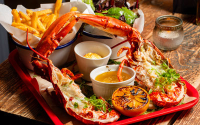 seafood tray with lobster, sauces, piece of orange and chips, served on wooden table at Crabshack Worthing