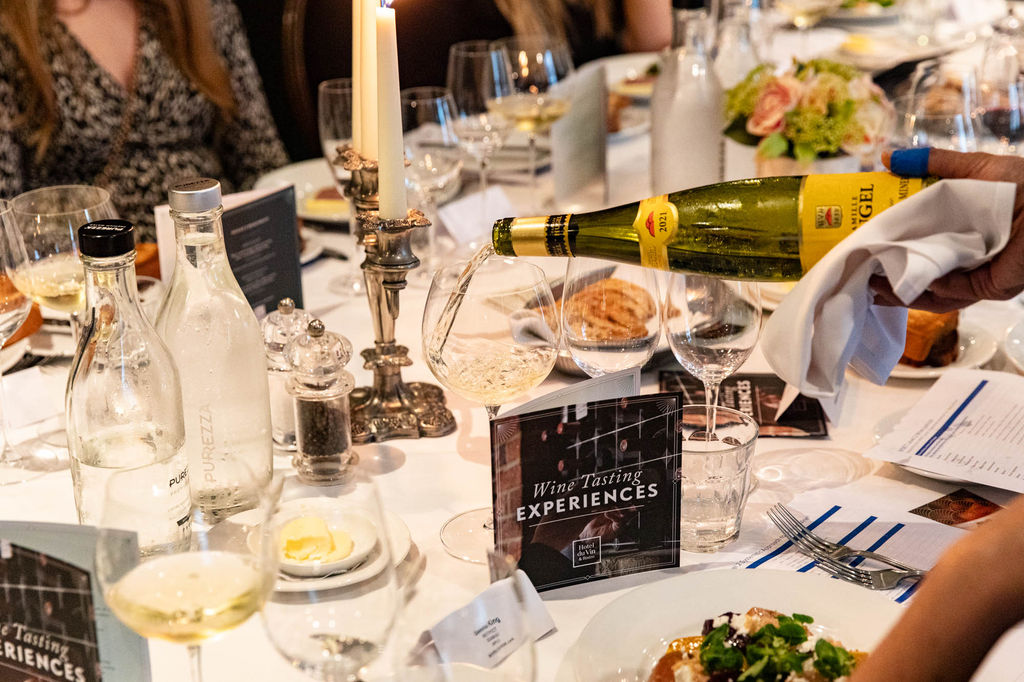 White wine being poured into a glass on a table with lots of plates of food and glasses of wine. Venue Hire in Brighton. Brighton Venue Hire: The Perfect Spaces for Every Occasion