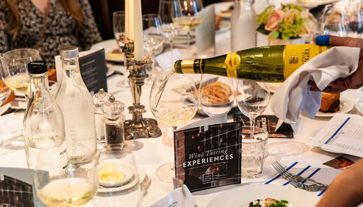 White wine being poured into a glass on a table with lots of plates of food and glasses of wine. Venue Hire in Brighton. Brighton Venue Hire: The Perfect Spaces for Every Occasion