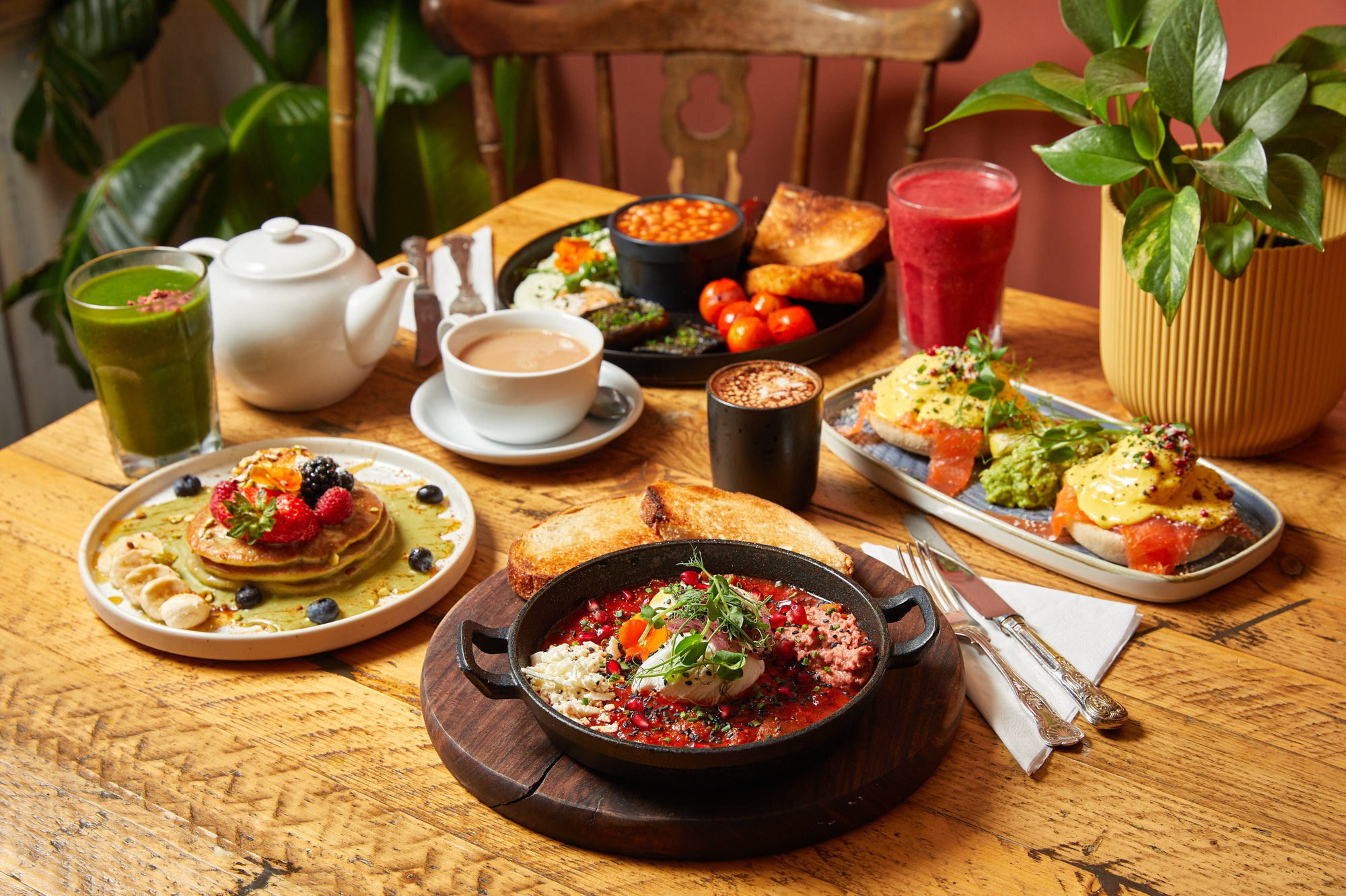 side shot of various dishes on the table including full english, pancakes, toast, smoothies and coffee