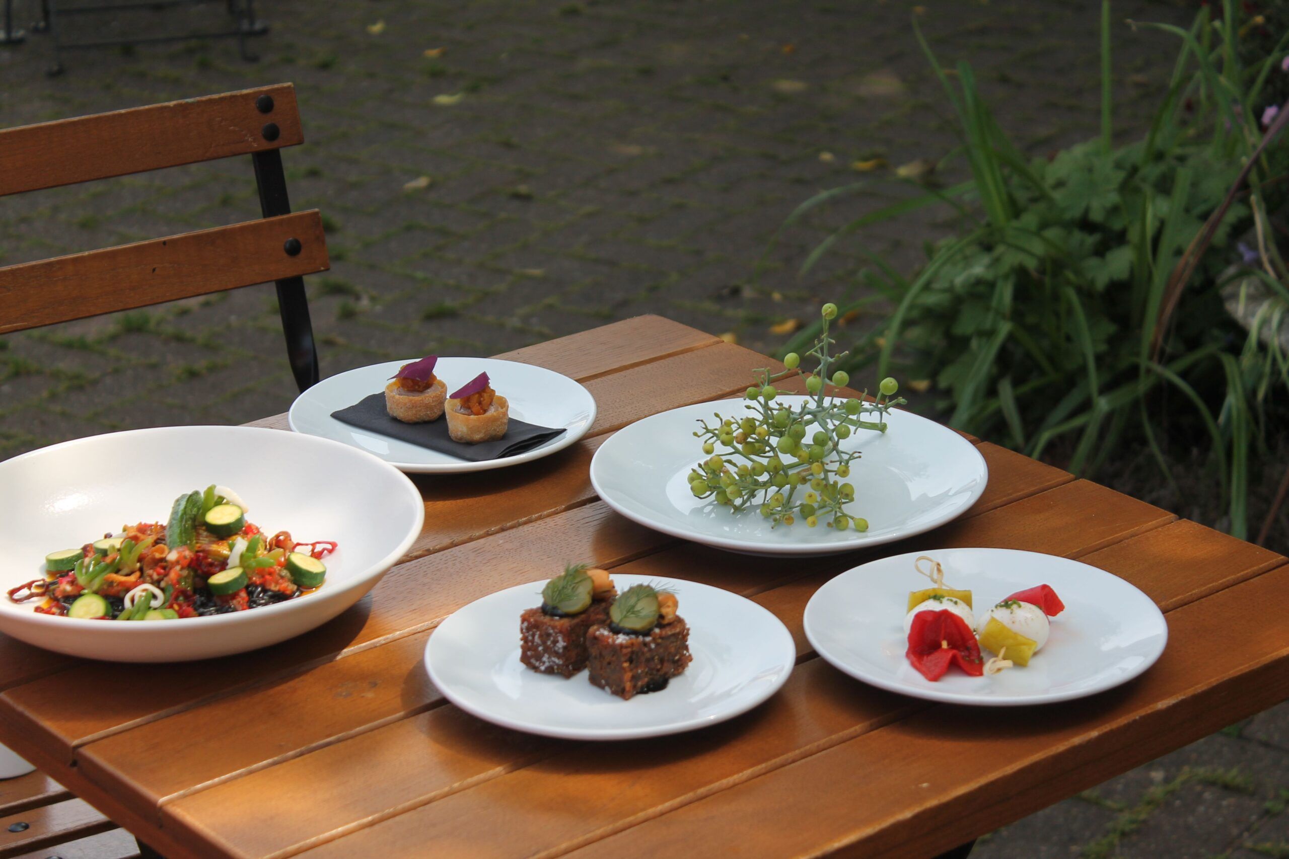 few small plates served on the wooden table in the garden 