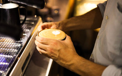 hands holding a flat white coffee