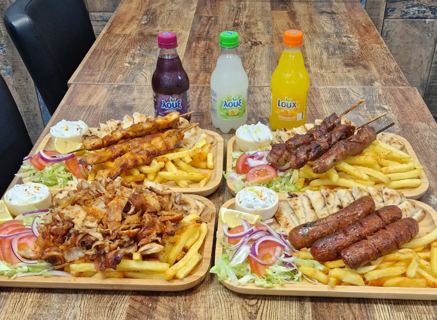 table laid out with platters with meet and chips and there are few fizzy drinks served 