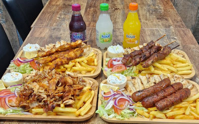 table laid out with platters with meet and chips and there are few fizzy drinks served
