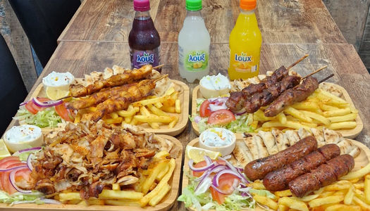 table laid out with platters with meet and chips and there are few fizzy drinks served