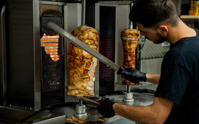 a man cutting of the meat of the metal stick at Parthenon Gyros