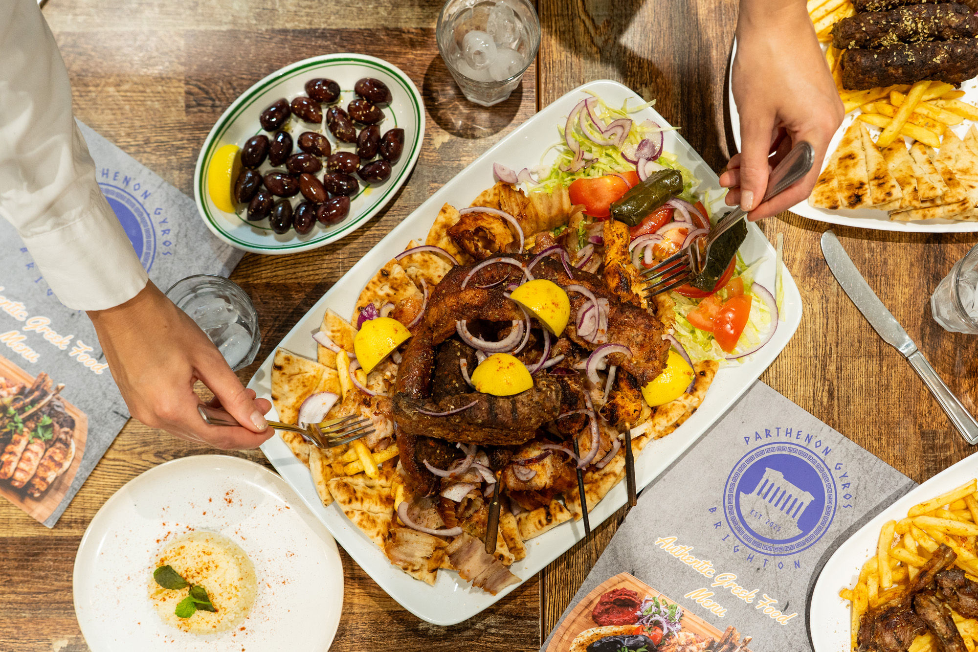 hands picking up food from the sharing platter at Parthenon Gyros