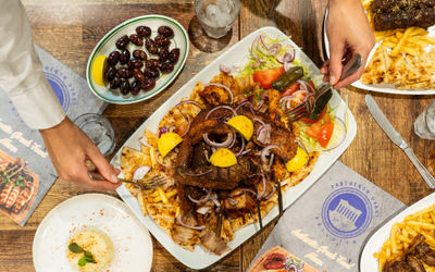 hands picking up food from the sharing platter at Parthenon Gyros