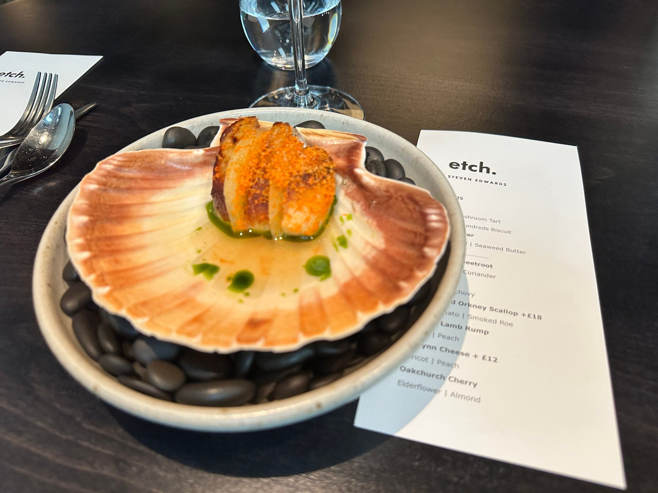 close up shot of the scallop dish of the edit menu served in. grey bowl