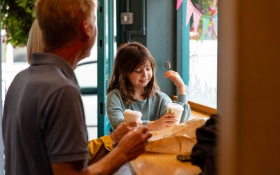 girl having a hot chocolate with her parent