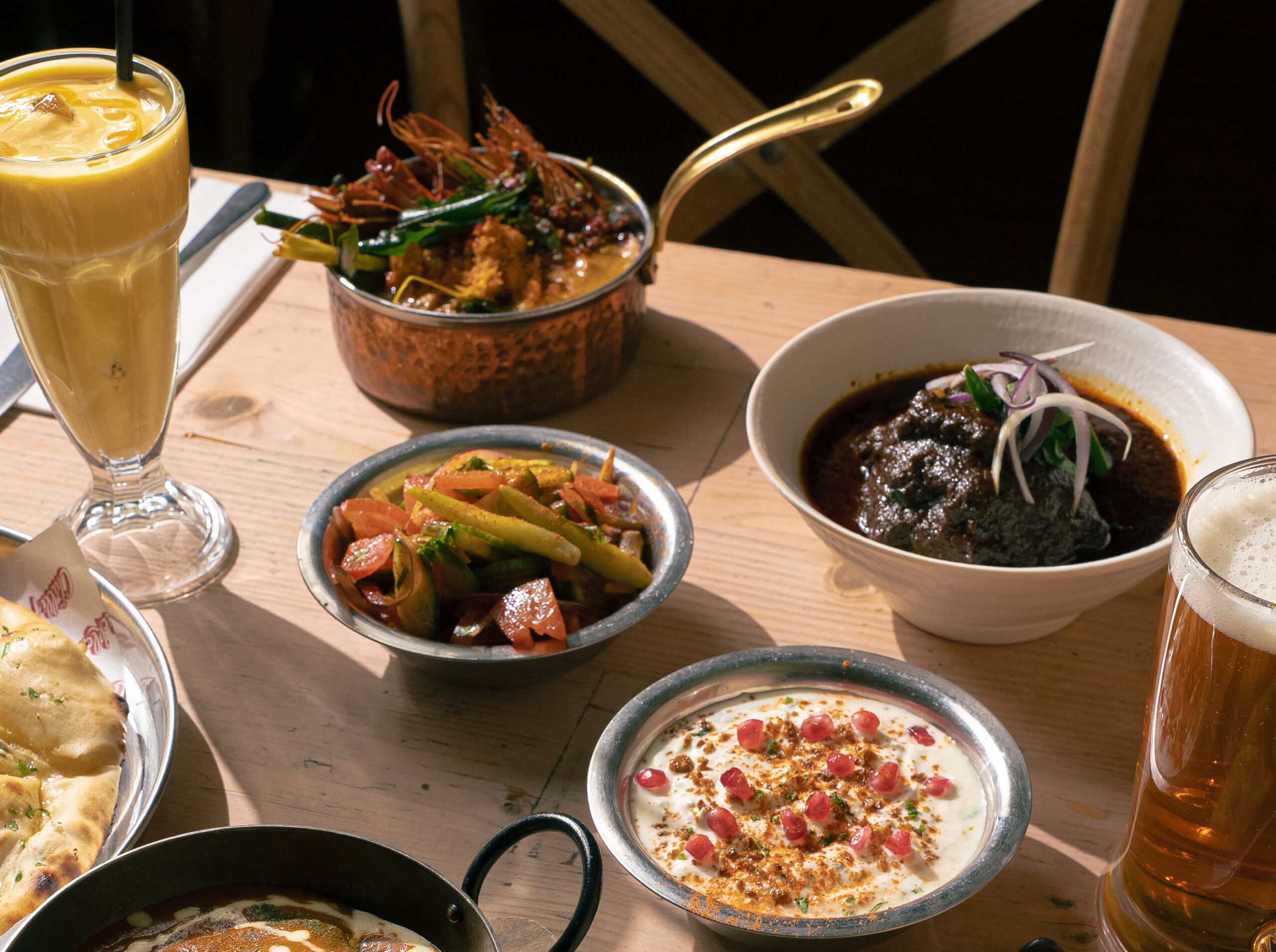 A vibrant spread of Indian dishes on a table at The Chilli Pickle, featuring colorful curries, naan and accompaniments