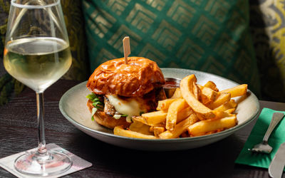 burger and chips served on the gray plate with glass of white wine