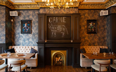 interior of Carne in Hove, dim lights, light seating, decorative fire place, paintings on the wall