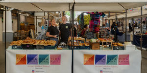 A colourful display of Swedish buns and pastries from Fika Bakery at Brighton Open Market, arranged on trays against a vibrant background—showcasing cinnamon buns, cardamom swirls, croissants, and other freshly baked Scandinavian treats.