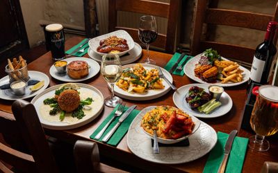 side shot of the table filled out with various dishes including sausage and mash, veggies, cron and chips dish, pie and drinks