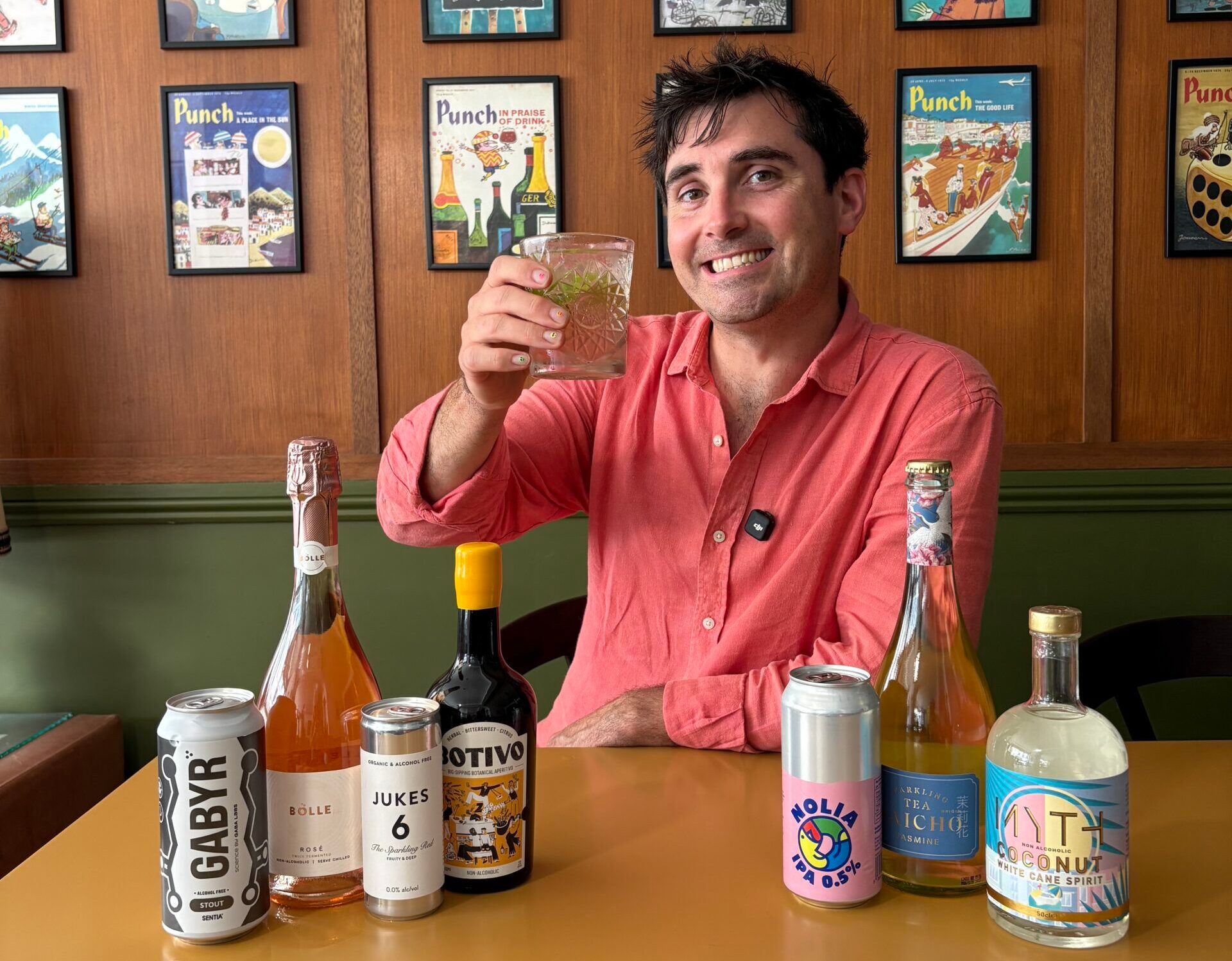 Tom Surgey having a glass of drink, sitting by the wooden table