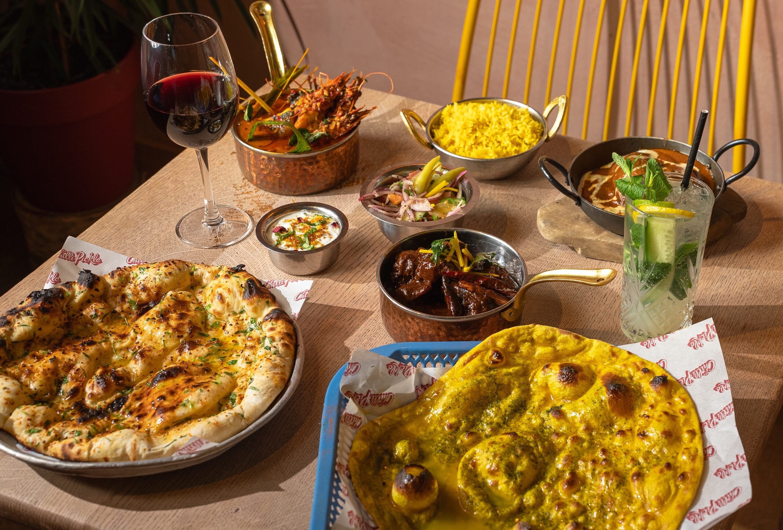 a selection of dishes at Chilli Pickle Brighton, A couple of naan breads alongside smaller dishes. 