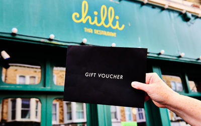 A black envelope held up in front of the green exterior of a Hove restaurant.