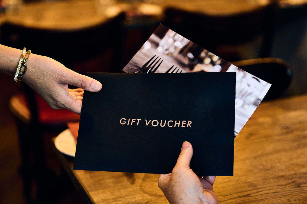 A close up of peoples hands holding a gift voucher.