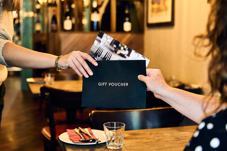 Two people passing a gift voucher in a restaurant to each other.