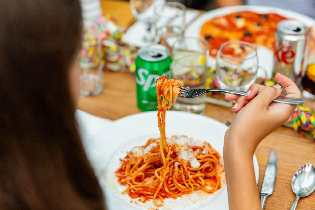 hand picking up pasta covered in red sauce