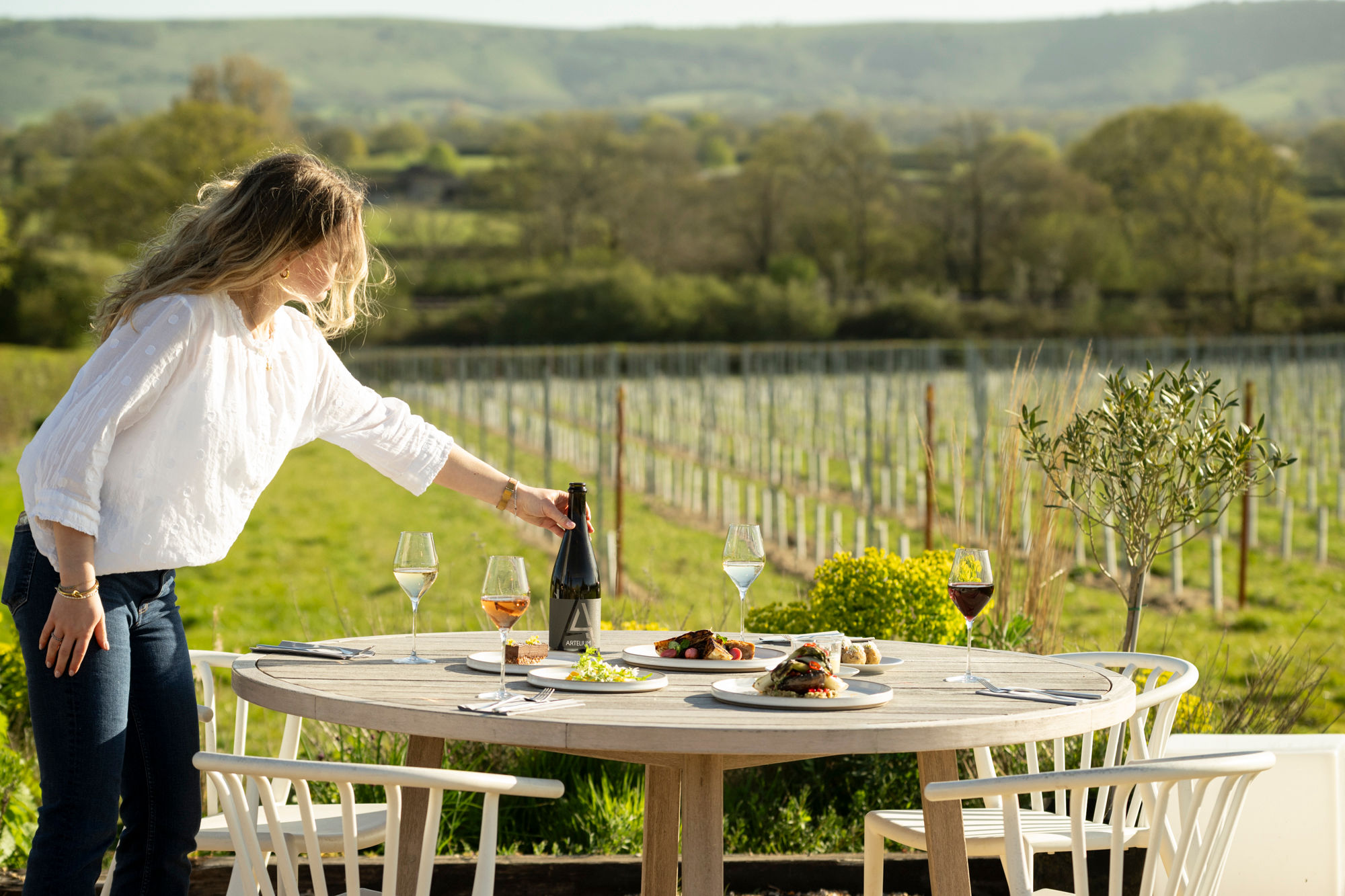Artelium Kitchen - waiter adding bottle of champage on the table in the yard