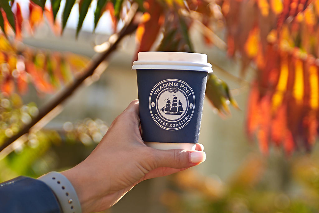 Coffee in a takeaway cup in Brighton Pavilion gardens with autumn leaves in the background.