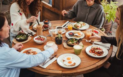 People sat around a large round table at Coppa Club Brighton with lots of dishes of food.