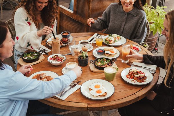People sat around a large round table with lots of dishes of food.