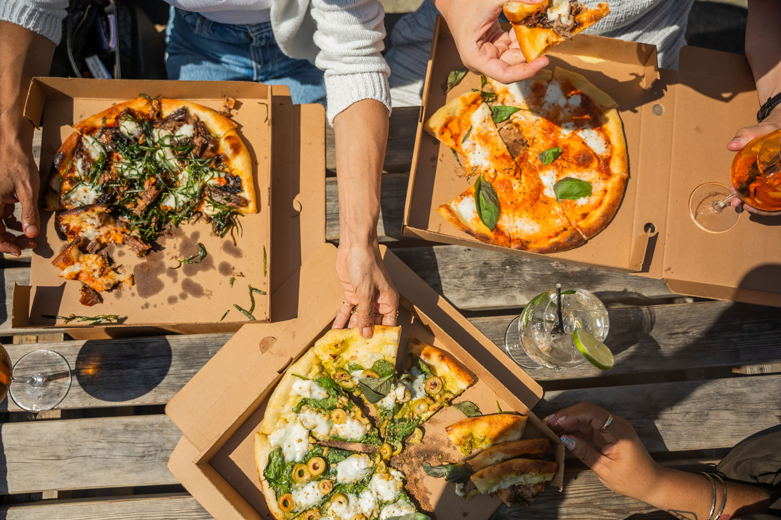 over head shot of the three people sharing three pizzas at White Horses