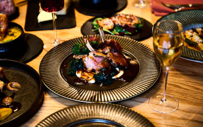 Lamb dish with gravy and glasses of wine on a table at Terra Restaurant at Tottington Manor, Sussex.