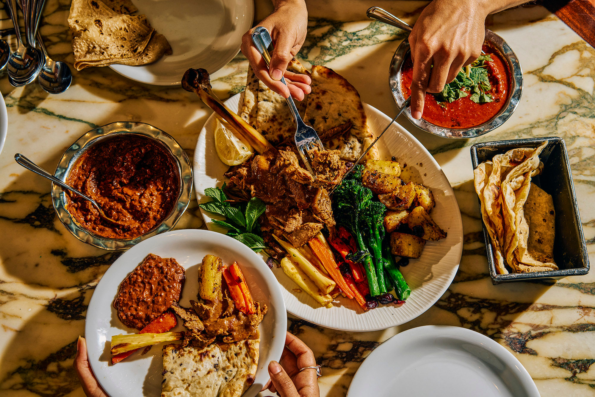 Overhead photo of a festive feast with lots of food and people tucking in.