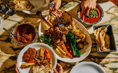 Overhead photo of a festive feast with lots of food and people tucking in.