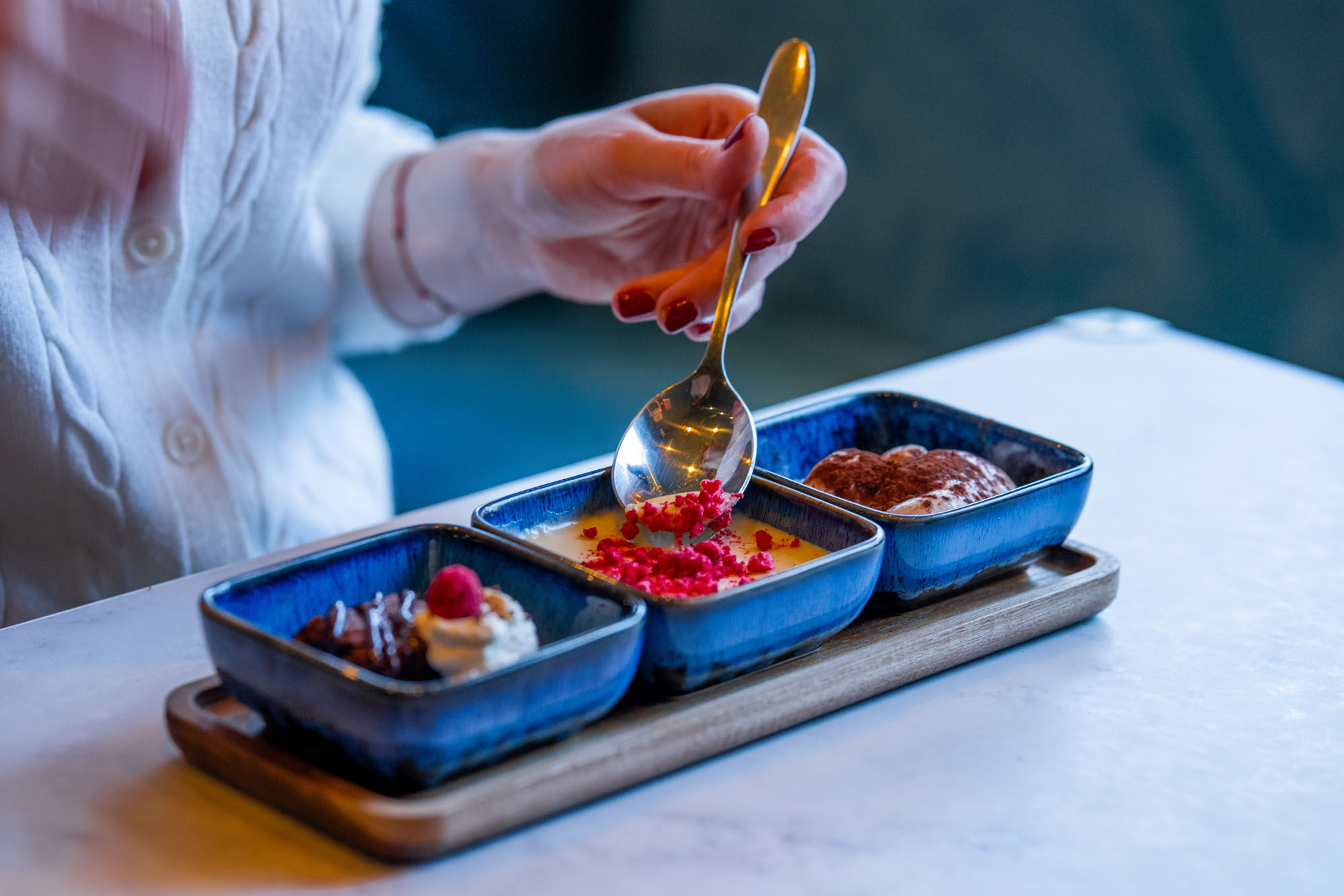 three type of desserts seved in small blue squared bowls