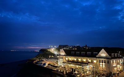 white horses an image of a The White Horses hotel and restaurant in Rottingdean at dusk. The sky is inky blue and the lights from the hotel and restaurant give a warm inviting glow.
