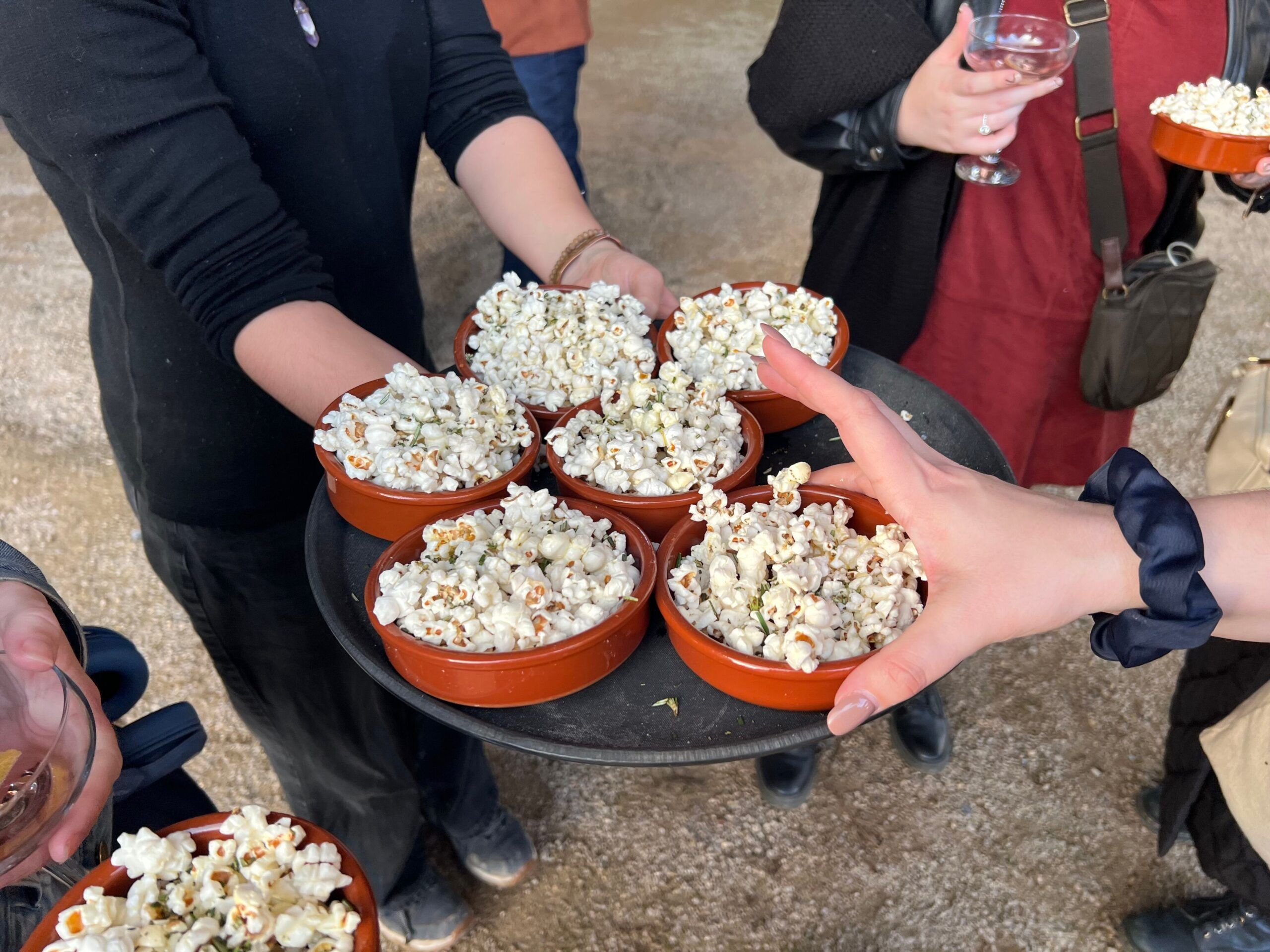 a person handing over popcorn in the bowls to participants of A Feast Over Fire event