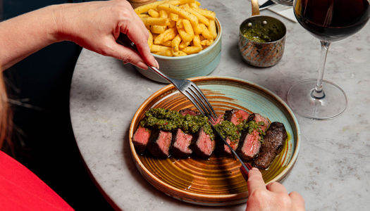 person cutting steak bits on the plate. This lunch is voted the best lunch in Brighton and Hove in 2026 at the BRAVO Awards. Kindling Restaurant